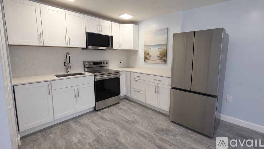 A kitchen with white cabinets and a grey refrigerator.
