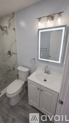 A bathroom with a toilet, sink, and mirror.