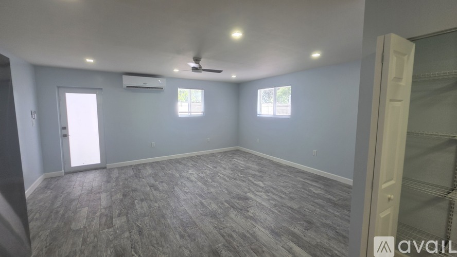A room with a ceiling fan and two windows.