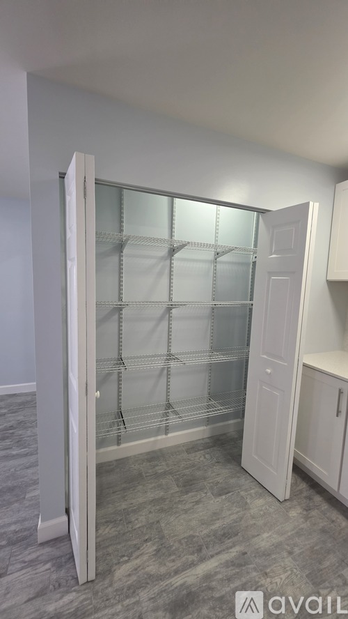 A white pantry with a glass door cabinet.