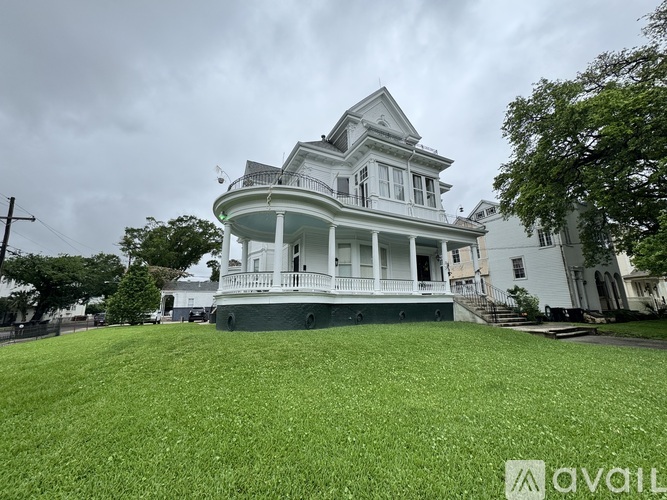 A white Victorian-style house with a green lawn in front.