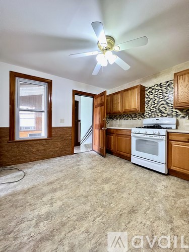 A kitchen with a white stove top oven and wooden cabinets.