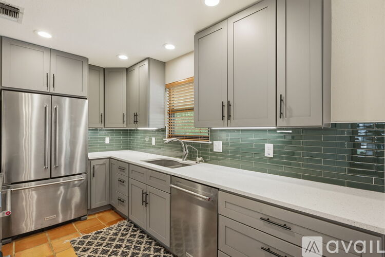 A kitchen with a stainless steel refrigerator and cabinets.