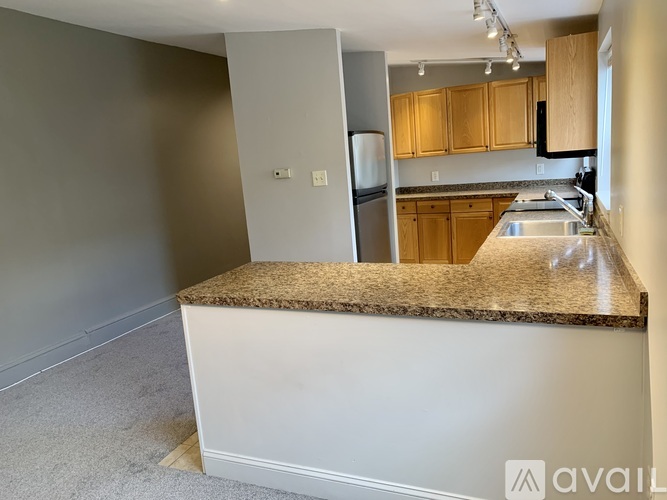 A kitchen with a granite countertop and a refrigerator in the background.