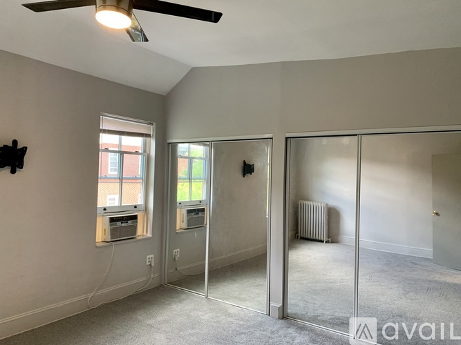 A room with a ceiling fan and a mirrored wall.