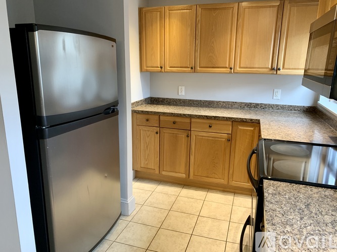 A kitchen with a black fridge and wooden cabinets.