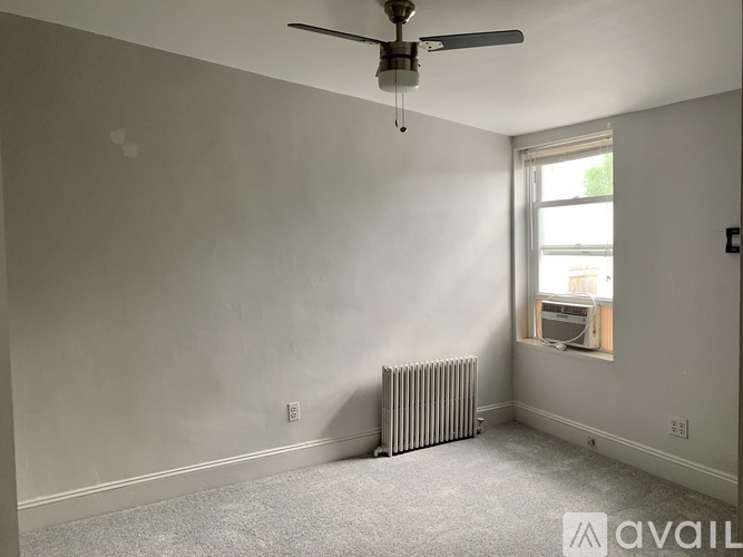 A room with a ceiling fan and a window with a view of a building outside.