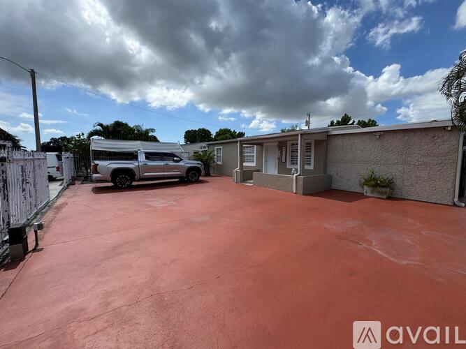 A red-painted driveway leads to a house with a silver SUV parked in front.