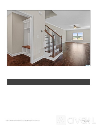 A spacious room with wooden floors and a staircase leading to another level.