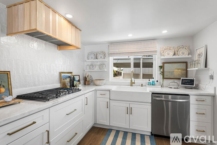 A kitchen with white cabinets and a wooden range hood.