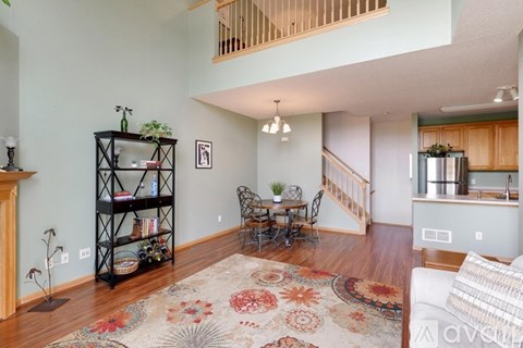 A living room with a rug on the floor and a dining table with chairs.
