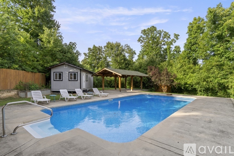 A pool with a house and chairs in the background.