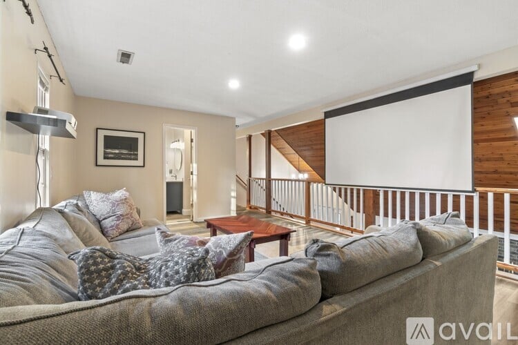 A living room with a grey couch and a wooden staircase.