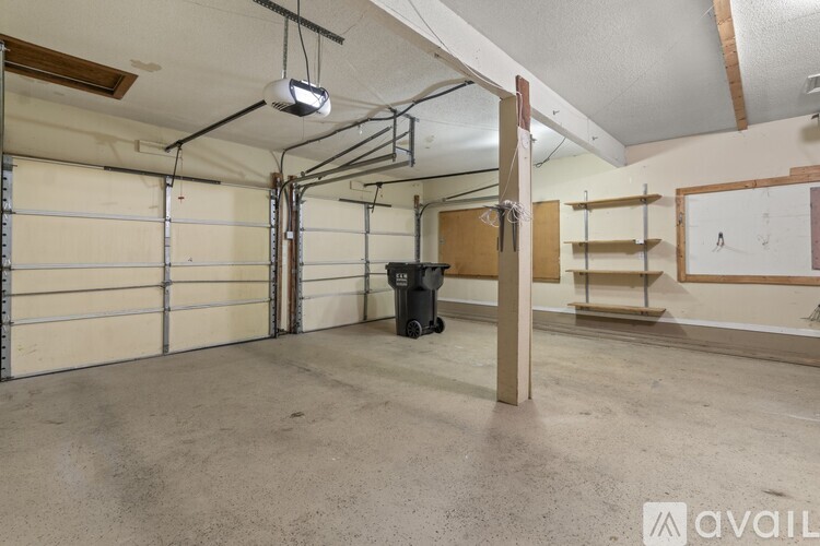 A spacious garage with a trash bin and a light hanging from the ceiling.
