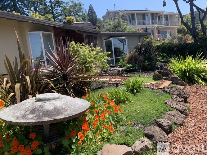 A garden with a stone path and a grey umbrella.