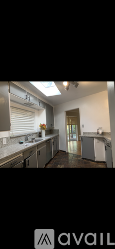 A kitchen with a skylight and a countertop with a vase of flowers.