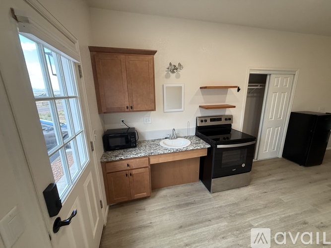 A kitchen with wooden cabinets and a black refrigerator.