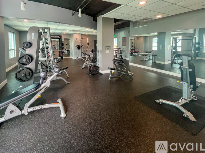 A gym with a variety of equipment including a weight bench, a leg press machine, and a squat rack.