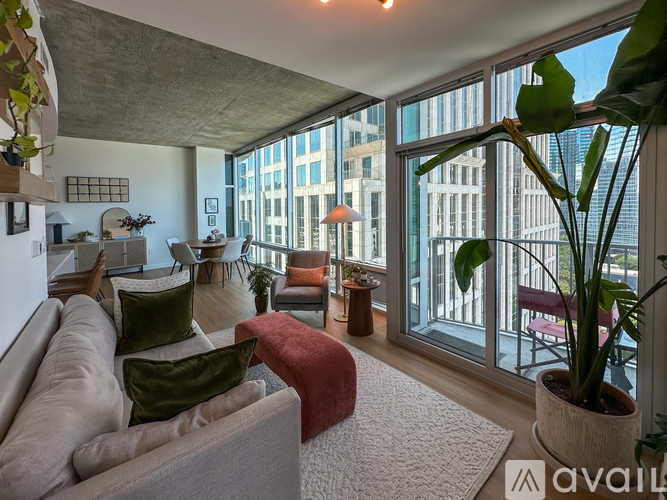 A living room with a couch, a chair, a potted plant, and a large window.