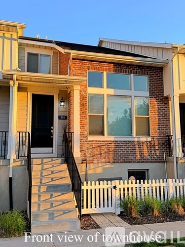 A front view of a townhouse with a black door and a white fence.