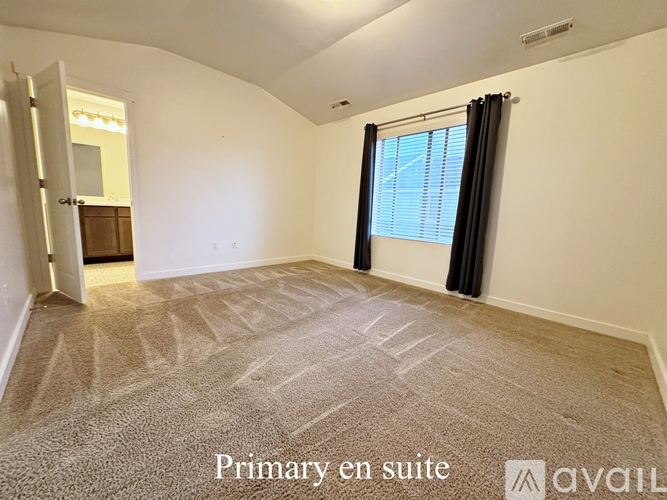 A room with a carpeted floor and a window with black curtains.