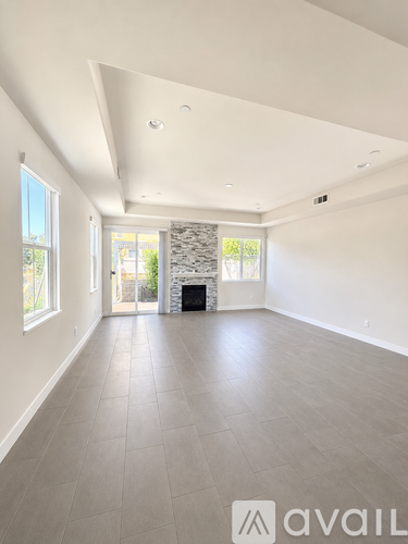 A spacious living room with a fireplace and a stone wall.
