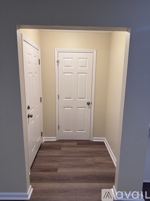 A hallway with two doors and a wooden floor.
