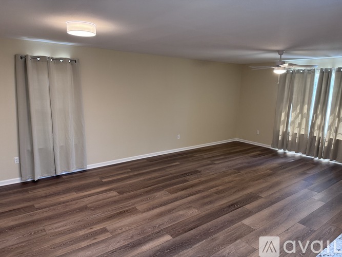 A room with wooden flooring and white curtains.