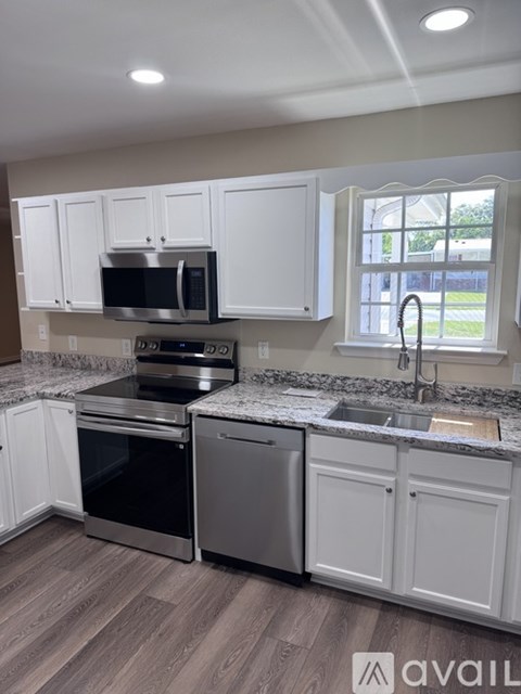 A kitchen with white cabinets and a granite countertop.