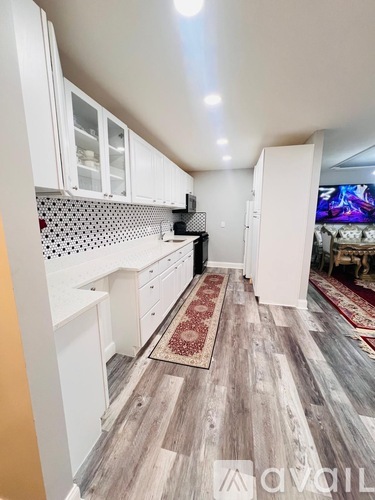 A kitchen with white cabinets and a wooden floor.