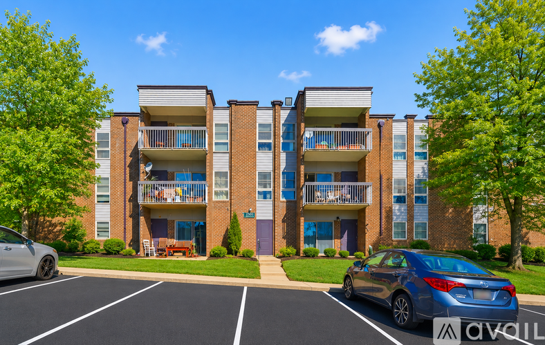A car is parked in a parking lot in front of a brick apartment building.