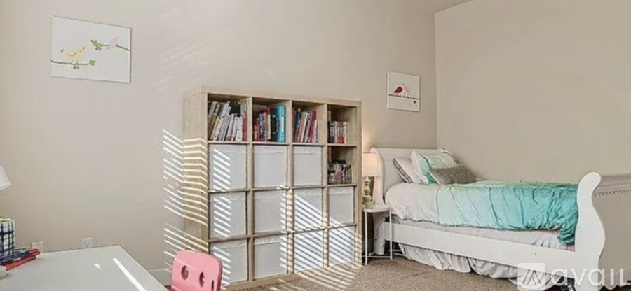 A bedroom with a bed, a bookshelf, and a painting on the wall.