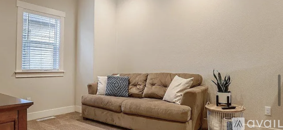 A living room with a beige couch and a small table with a plant on it.