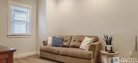 A living room with a beige couch and a small table with a plant on it.