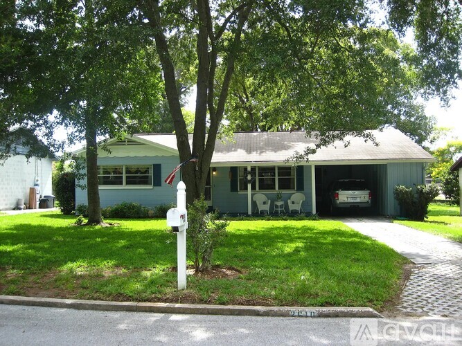 A green house with a white fence and a mailbox in front.