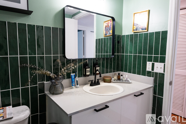 A bathroom with a green tiled wall and a white sink.