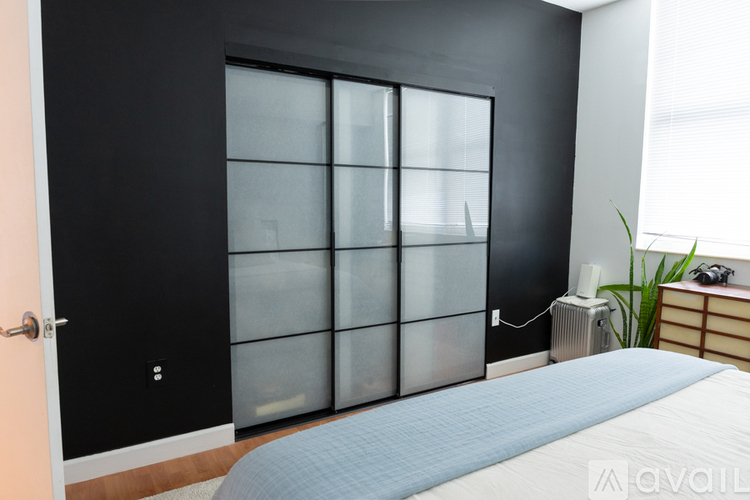 A bedroom with a bed, a black door, and a glass cabinet.
