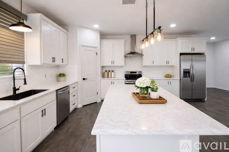 A kitchen with white cabinets and a marble countertop.