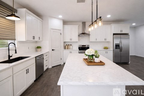 A kitchen with white cabinets and a marble countertop.
