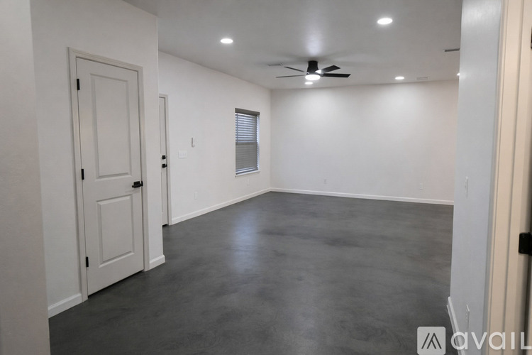 A spacious room with a ceiling fan and a door.