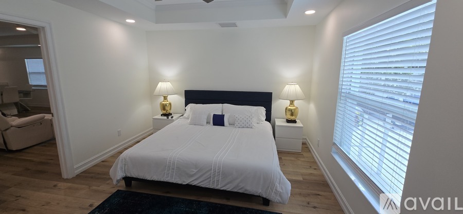 A bedroom with a large bed and two lamps.