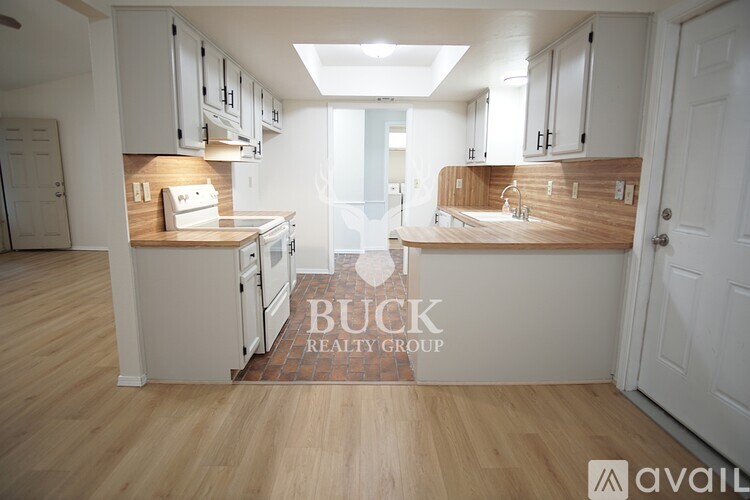 A kitchen with white cabinets and wooden floors is on the market.