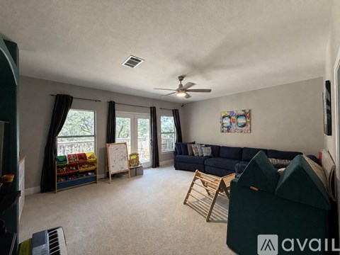 A living room with a black couch and a ceiling fan.