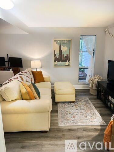 A living room with a white couch and a rug in front of it.