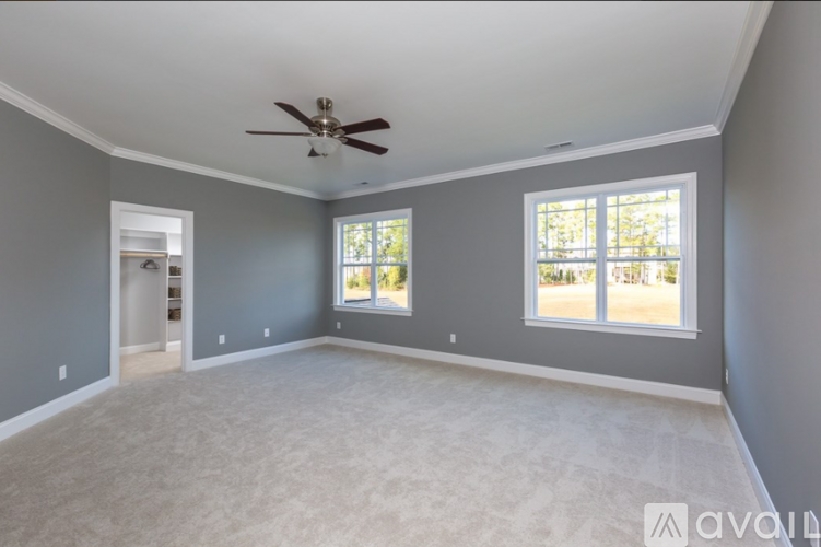 A spacious room with a ceiling fan and two windows.