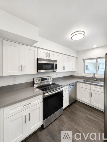 A modern kitchen with white cabinets and stainless steel appliances.