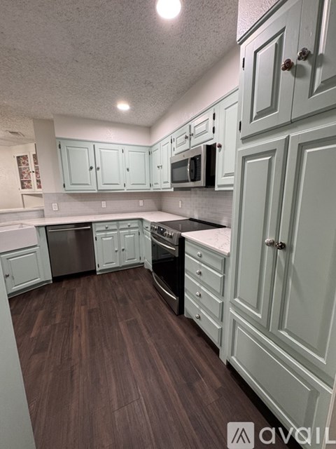 A kitchen with white cabinets and a wooden floor.