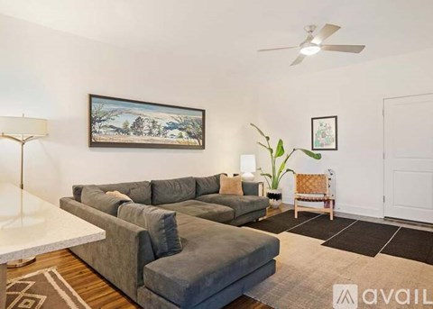 A living room with a grey couch and a painting on the wall.
