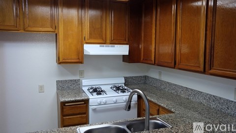 A kitchen with a white stove and wooden cabinets.