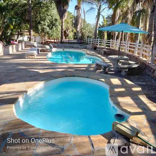 A swimming pool with a blue umbrella and a white fence in the background.